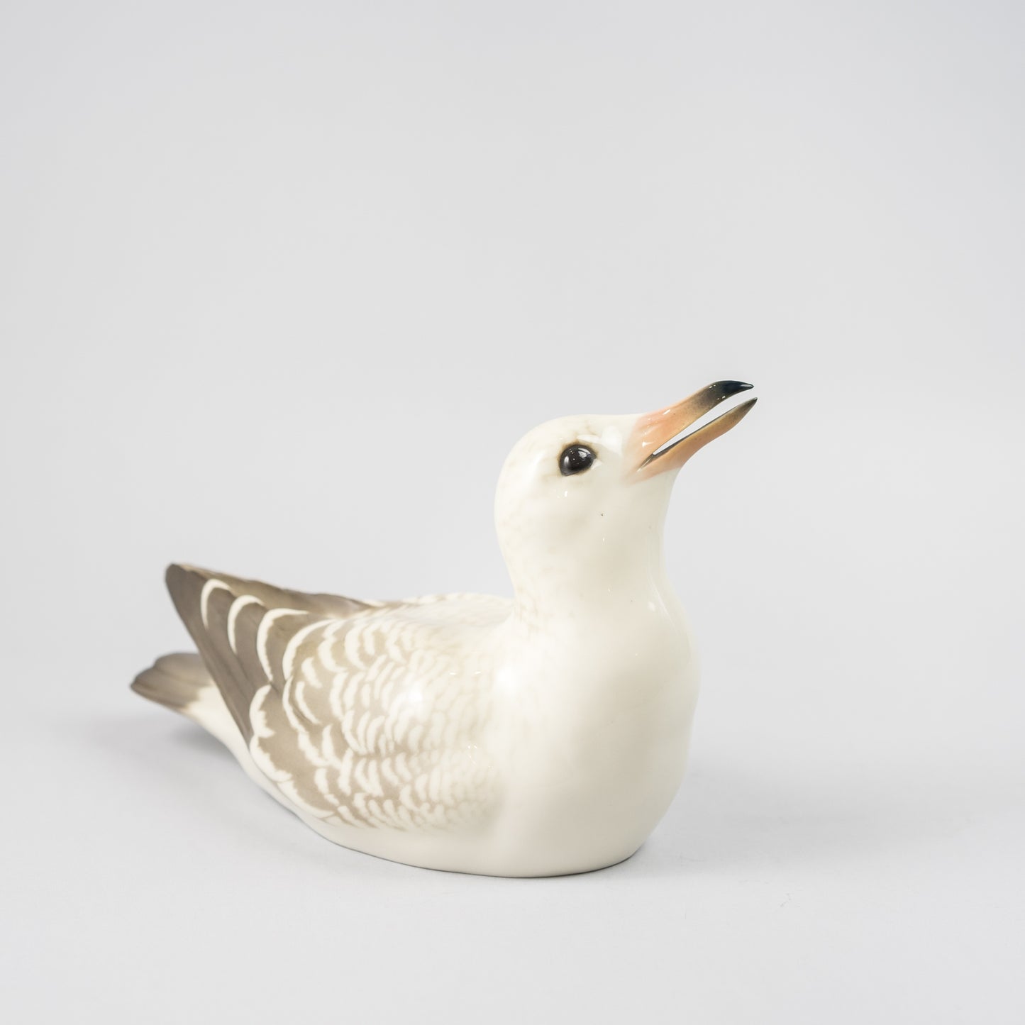 Mås i underglasyrteknik, 1920-tal. Tillverkad på Rörstrand och såld hos Löfbergs i Malmö. 11,5cm hög och 19cm lång. Gull in porcelain painted with underglazed technic, 1920's. Made by Rörstrand. H: 11,5cm/4,5" and W: 19cm/7,5".
