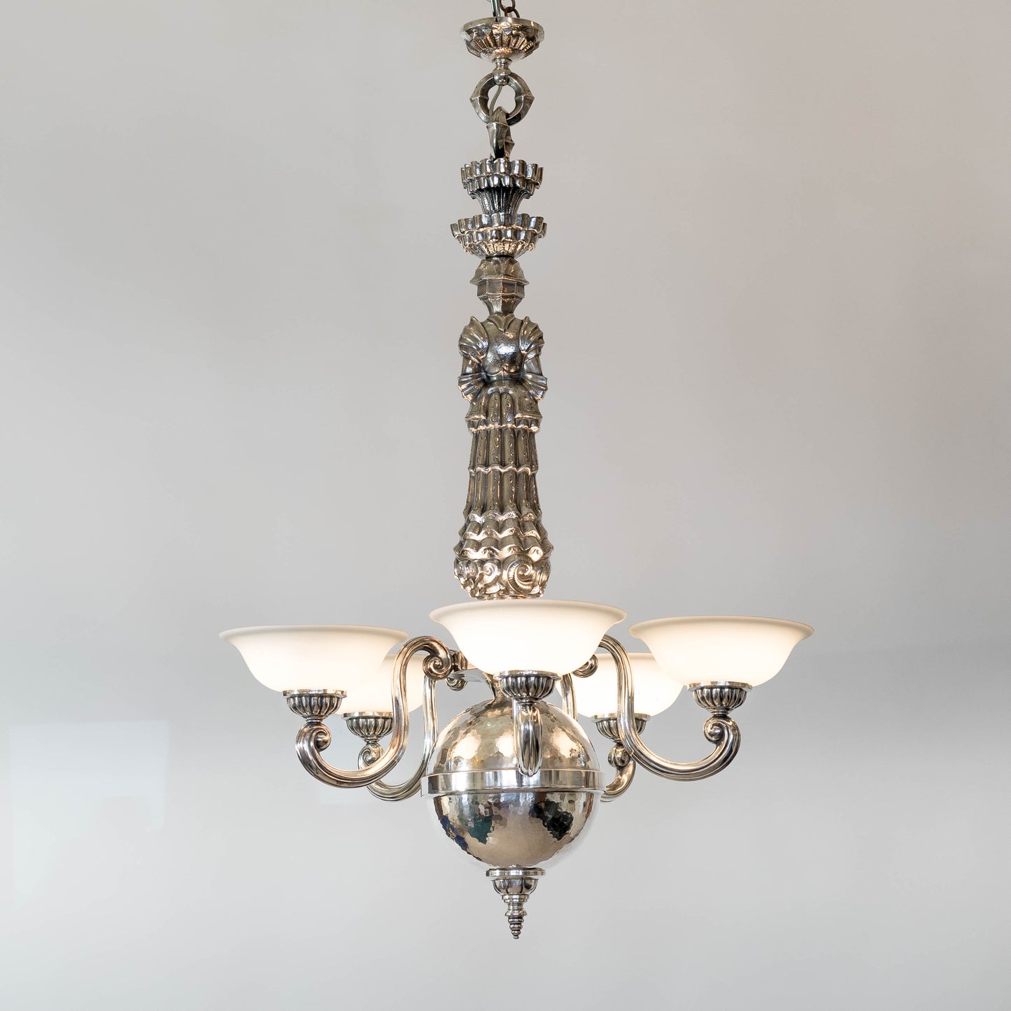 Taklampa i vitmetall, av Per Torndahl för Atelier Torndahl med motivet S:t Göran och draken, 1920-tal. H: 115cm och diam. 70cm. Per Torndahl ceiling light "Staint George and the dragon" for Atelier Torndahl, 1920's. H: 115cm/45,3" and diam. 70cm/27,6"