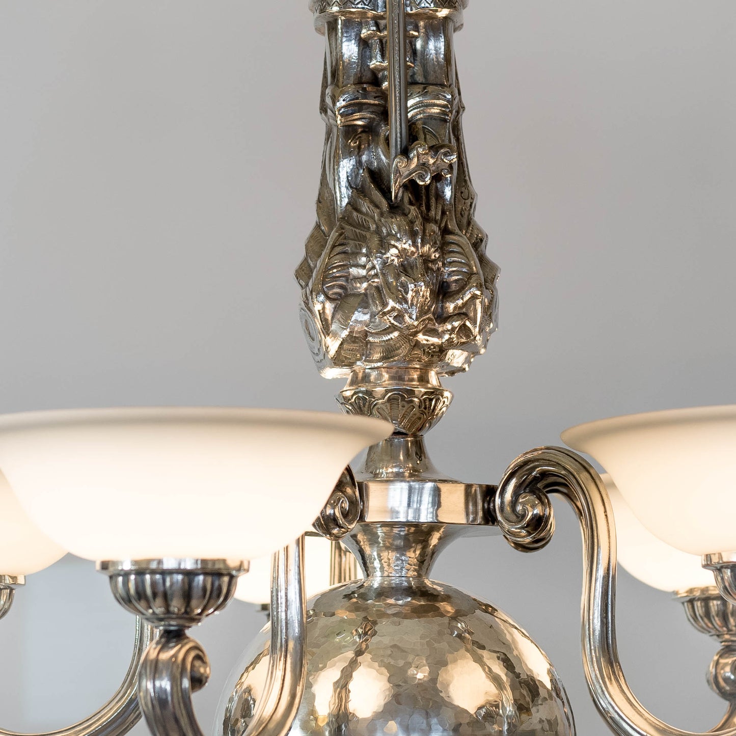 Taklampa i vitmetall, av Per Torndahl för Atelier Torndahl med motivet S:t Göran och draken, 1920-tal. H: 115cm och diam. 70cm. Per Torndahl ceiling light "Staint George and the dragon" for Atelier Torndahl, 1920's. H: 115cm/45,3" and diam. 70cm/27,6"